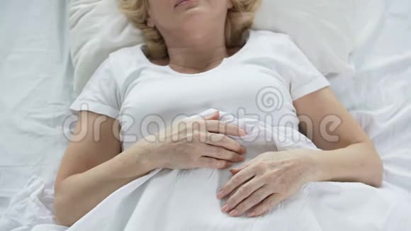睡在床上的老妇人布满皱纹的双手退休视频的预览图