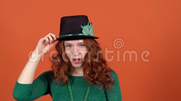 年轻女子戴着帽子在橙色的墙上庆祝圣帕特里克节视频的预览图