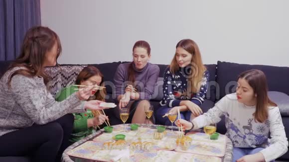 年轻女孩晚上在一起在家吃寿司视频的预览图