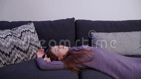 漂亮的年轻女子躺在客厅的沙发上看着摄像机视频的预览图