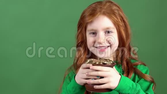 女孩红发庆祝圣帕特里克天绿墙背景举行幸运罐视频的预览图