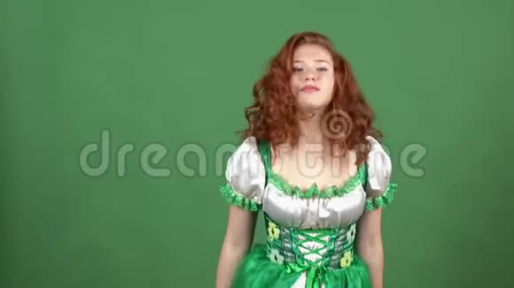 年轻女子在绿墙上庆祝圣帕特里克一天穿着传统服装换发视频的预览图