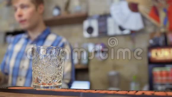 酒吧柜台上的空杯子酒吧老板在模糊的背景下准备鸡尾酒视频的预览图