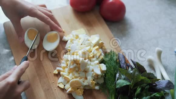 在木板上用刀切煮鸡蛋把煮好的手合上食物概念视频的预览图
