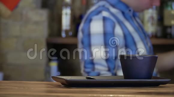 酒吧柜台上的空杯子酒保在模糊的背景上煮咖啡视频的预览图