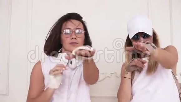 两位时尚的女性朋友都穿着白色的衣服戴着时髦的眼镜在白色的背景下一起跳舞视频的预览图