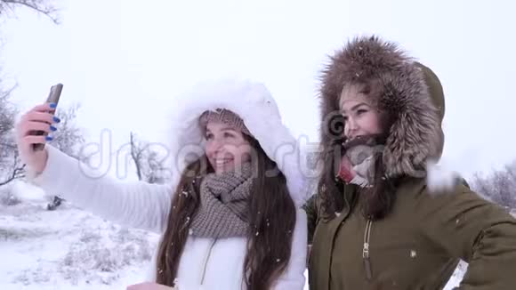 下雪的天气在下雪的背景下快乐的女人在电话里合影视频的预览图