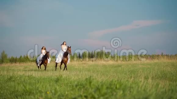 两个穿着白色连衣裙的女孩骑马女孩们骑马在田野上跳跃慢动作视频的预览图
