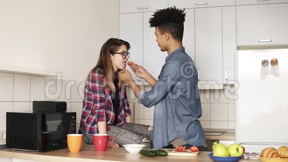 两个年轻人一起享受时光在舒适的厨房里做午餐一起生活穆拉托这家伙在喂视频的预览图
