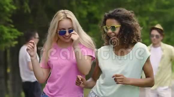 两个女朋友在公园的聚会上跳舞和聊天男人们喜欢夏天视频的预览图