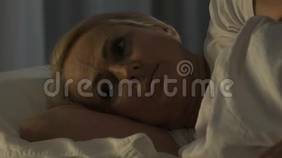 沮丧的老年妇女躺在床上思考家庭问题失眠视频的预览图