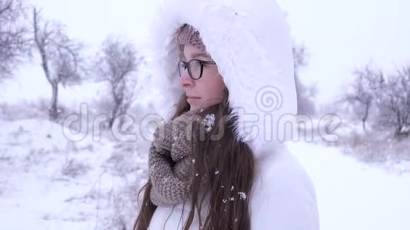 冬天站在雪下的可爱女眼镜的画像视频的预览图