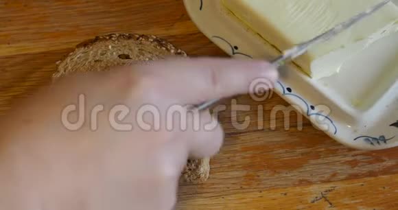 用刀子把黄油涂在一片面包上视频的预览图