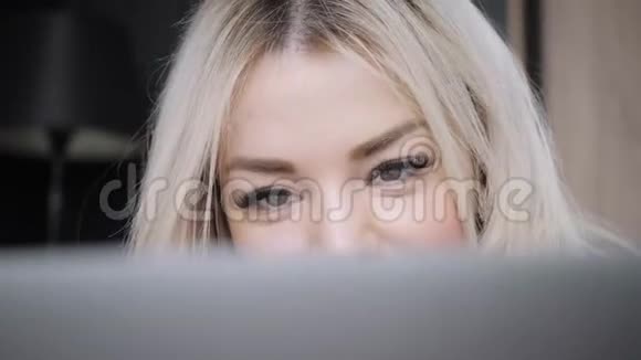 用灰色铝笔记本电脑躺在床上的美丽金发女人的特写肖像女孩微笑心情好博客视频的预览图