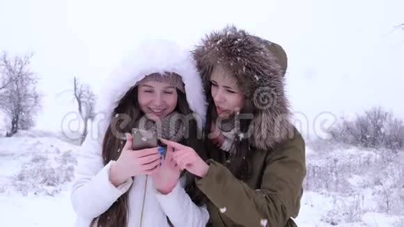 冬天迷人的女孩在下雪时坐在社交网络中使用小工具视频的预览图