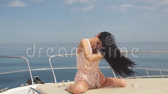 年轻美丽的黑发女子的肖像戴着太阳镜在帆船上的海洋背景上摆着姿势视频的预览图