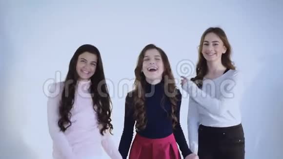 三个年轻女孩在白色背景的镜头下玩得很开心视频的预览图