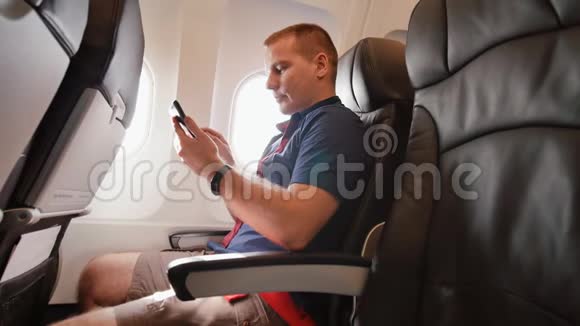 飞机上的年轻人在飞行前用手机交流视频的预览图