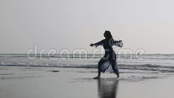 沙滩上与体操元素一起跳舞的年轻女子剪影视频的预览图