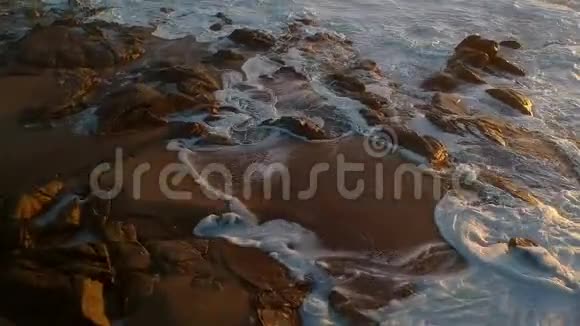 空中无人驾驶飞机在日落时迅速飞过岩石水流入海洋鸟飞到下面视频的预览图