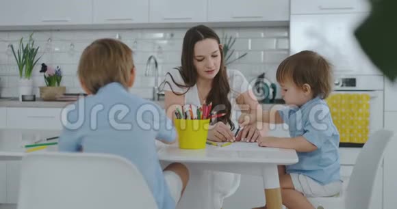 两个男孩的孩子和他的母亲坐在厨房里画画家庭幸福视频的预览图