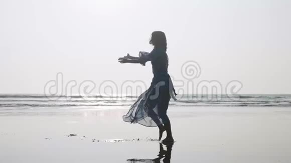 沙滩上与体操元素一起跳舞的年轻女子剪影视频的预览图