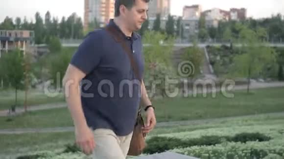 一个男人带着一个袋子急急忙忙地去公园和一个朋友见面视频的预览图