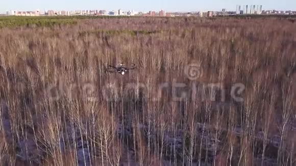 空中无人机直升机盘旋在天空上方的森林和城市街区的背景剪辑小型四架直升机视频的预览图