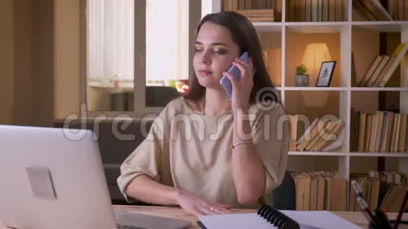 一位年轻迷人的高加索女商人在办公室里用笔记本电脑打电话的特写镜头视频的预览图
