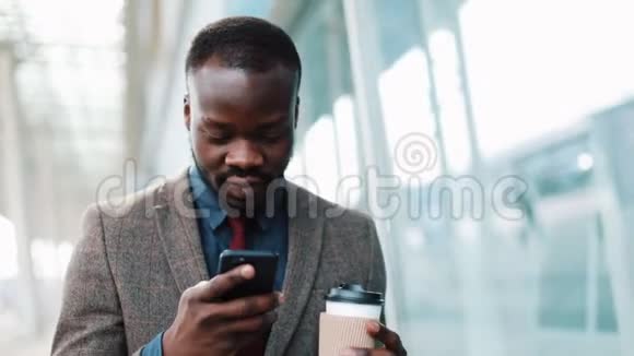 非裔美国人在他的智能手机中键入一些东西走在外面巴士司机走下机场候机楼使用视频的预览图