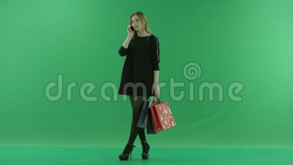 年轻健康的女士带着购物袋在手机上聊天颜色关键绿色背景视频的预览图