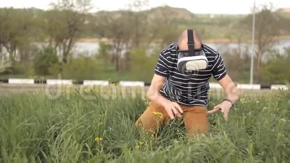 一个戴着虚拟现实头盔坐在草坪上的人潜水游戏或全景视频周围的电影和视频的预览图