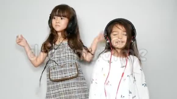 两个可爱的姐姐混合种族女孩享受音乐和耳机跳舞休闲活动视频的预览图