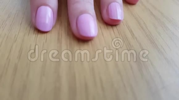 白色皮肤和粉红色短指甲的女性手抓着木桌视频的预览图