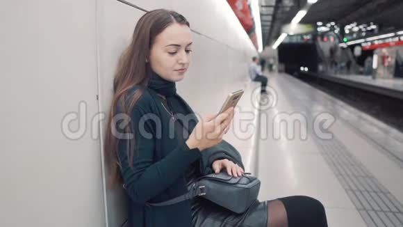 女人在地铁站打智能手机等待火车视频的预览图
