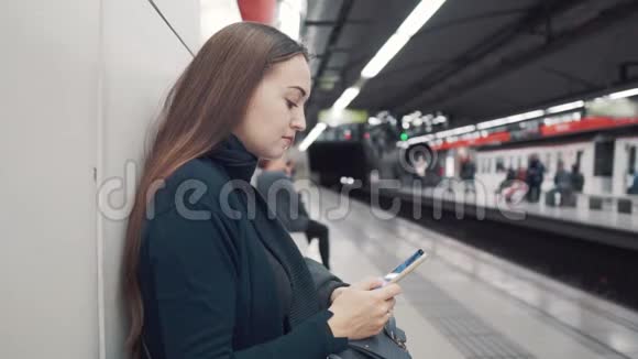 女人在地铁站打智能手机等待火车视频的预览图