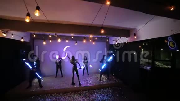 有领导的表演一队五名艺术家在舞台上用五彩纸屑覆盖巧妙地用发光的棍子编织视频的预览图