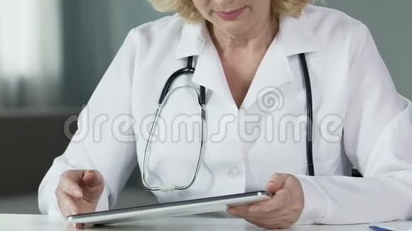 女性治疗师在平板电脑上滚动医疗文件现代技术视频的预览图