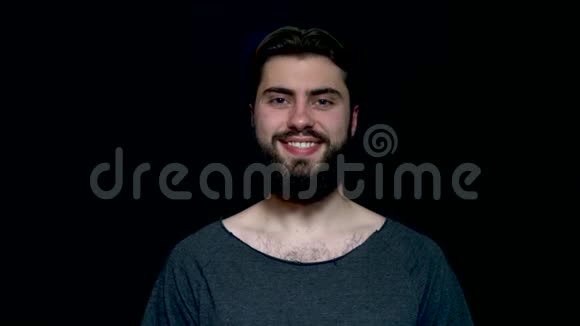 特写照片一个快乐的微笑胡须男子孤立在一个黑色的背景穿着灰色T恤的帅哥视频的预览图