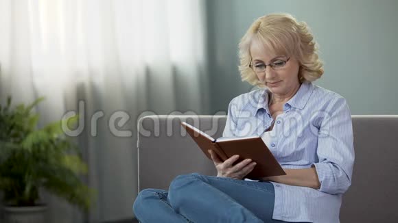 相当成熟的女性坐在沙发上阅读自我发展的书爱好视频的预览图