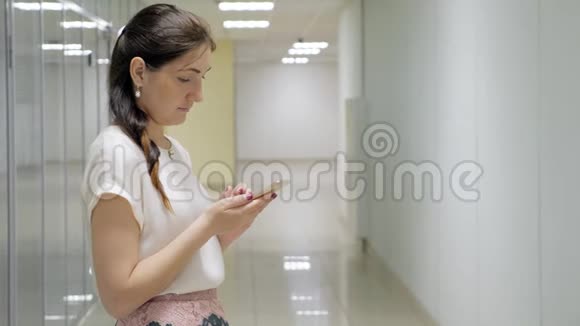 布鲁内特女士在一栋办公楼的走廊里拿着电话视频的预览图