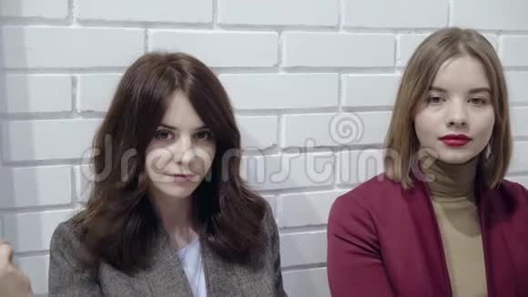 三个穿西装的年轻女人在白色墙边做鬼脸视频的预览图