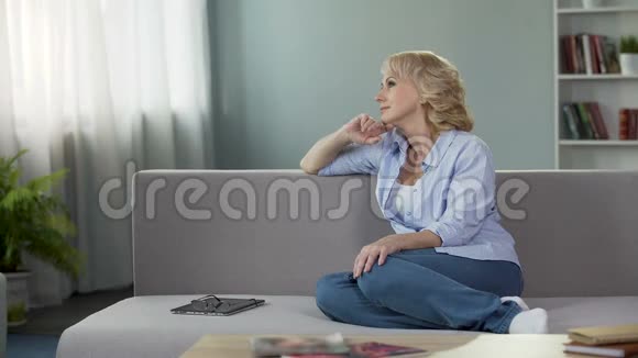 老年女性坐在沙发上梦想着暑假退休视频的预览图