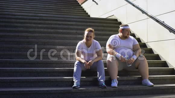 肥胖夫妇坐在楼梯上身体锻炼后精疲力竭聚在一起视频的预览图