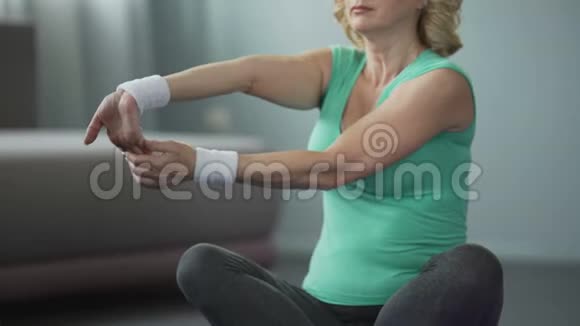 中年妇女坐在瑜伽垫上做练习练习莲花姿势视频的预览图