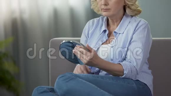 坐在沙发上看着手里的镜子年纪轻轻的退休妇女视频的预览图