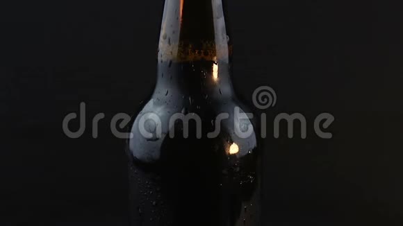 凝结水滴在黑暗的背景下从啤酒瓶中流出一瓶雾蒙蒙的啤酒视频的预览图