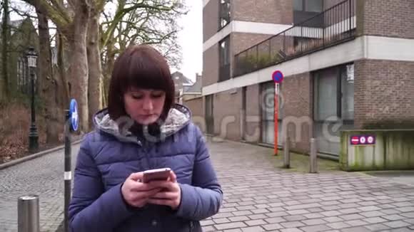 穿着智能手机在比利时布鲁日散步的女孩视频的预览图