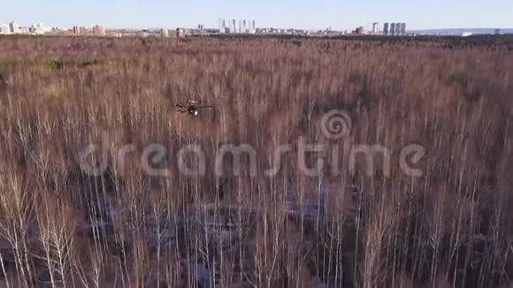 空中无人机直升机盘旋在天空上方的森林和城市街区的背景剪辑小型四架直升机视频的预览图