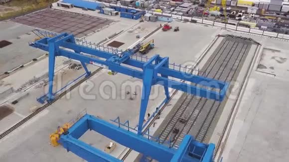 用于蓝色巨型龙门起重机站在钢轨和混凝土基础上剪辑仓库的俯视图视频的预览图